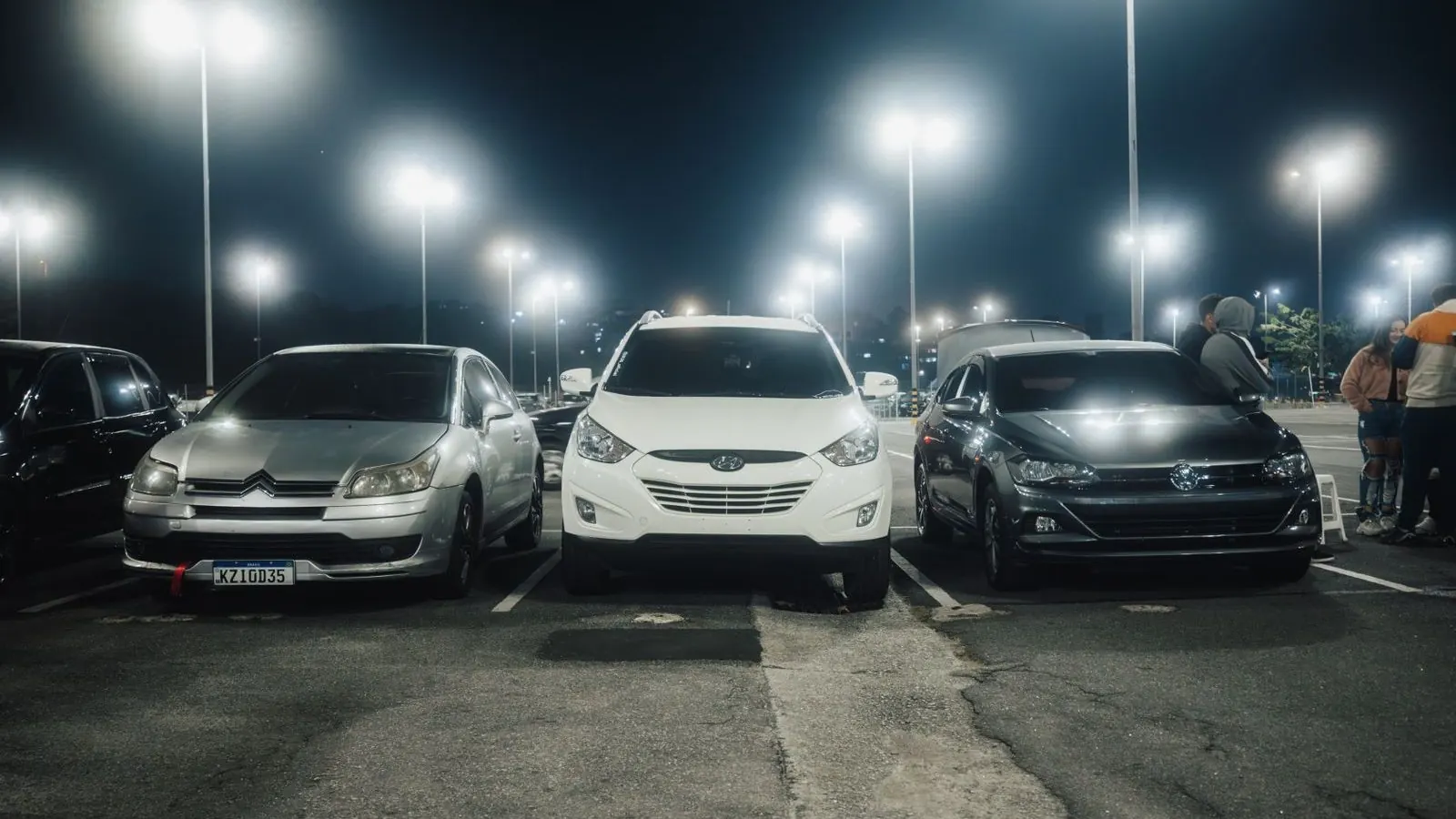 Veículos estacionados sob iluminação noturna, representando o cadastro de veículos consultado no DETRAN