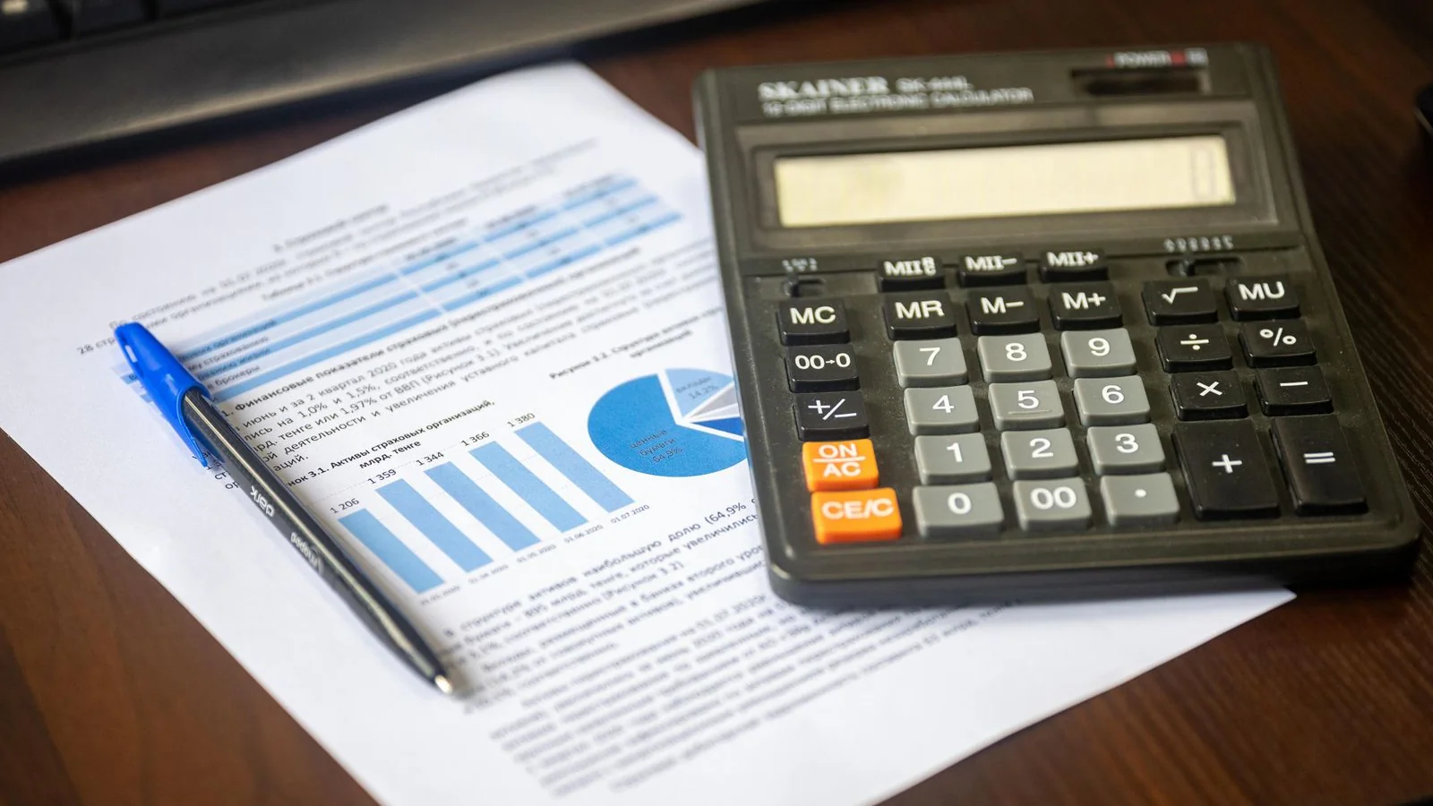 Calculadora, caneta e relatório financeiro sobre mesa, representando o cálculo do saldo devedor do financiamento